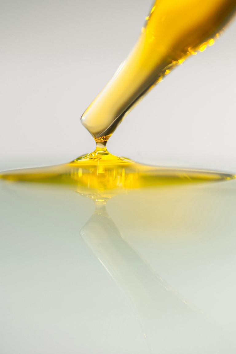 Huile d'olive dorée s'écoulant d'une pipette de laboratoire