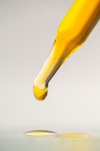 Goutte d'huile d'olive au bout d'une pipette de laboratoire