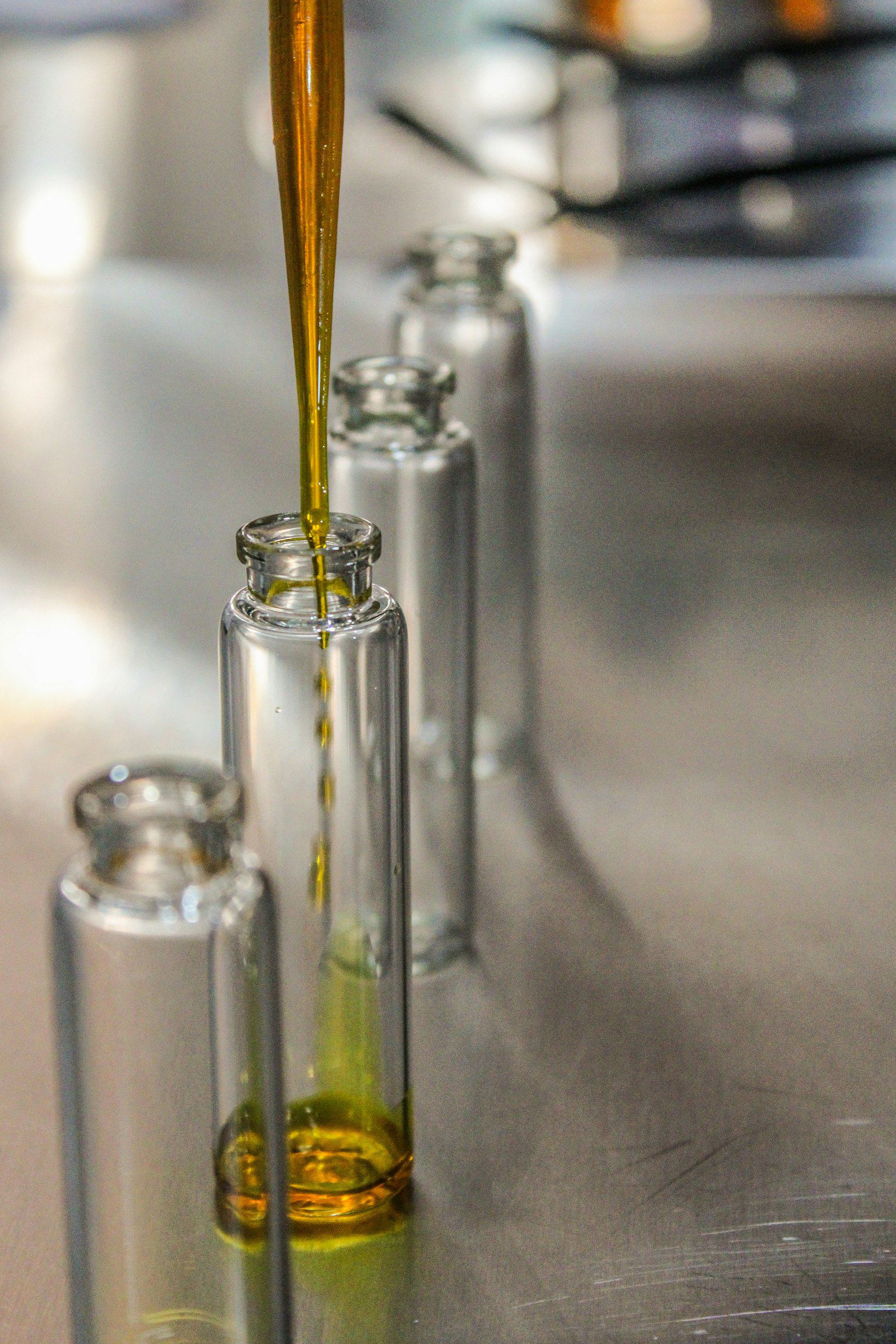 Huile d'olive versée dans de petits flacons d'échantillon en verre